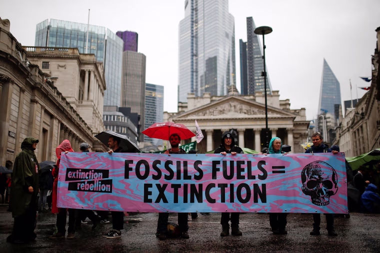 Image: Protesters hold a banner as they block the road during an Extinction Rebellion demonstration at Bank, in the City of London