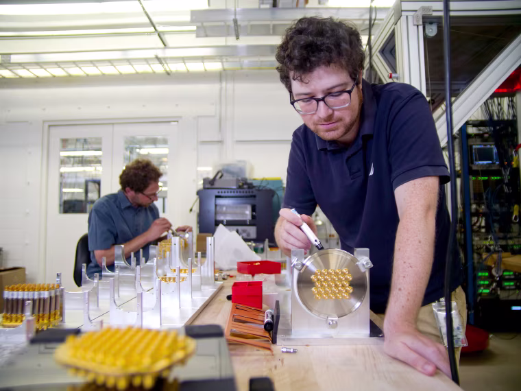 Research scientists Amit Vainsencher (front) and Ofer Naaman (back) at Google assembling and testing microwave cables to control qubits at ultra-low temperatures.