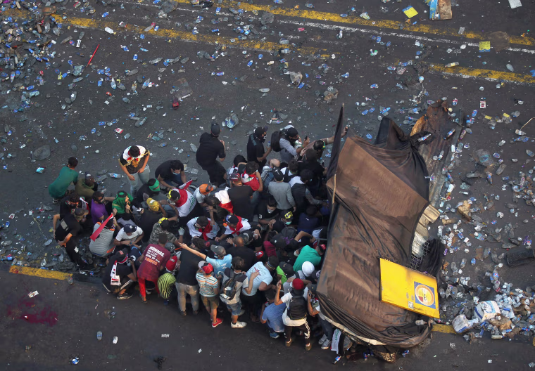 Image: Protesters take cover from security forces firing tear gas to keep demonstrators from storming Baghdad's Green Zone, which hosts government offices and foreign offices