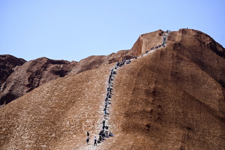 Image: Tourists climb Uluru, formerly known as Ayers Rock, at Uluru-Kata Tjuta National Park in the Northern Territory