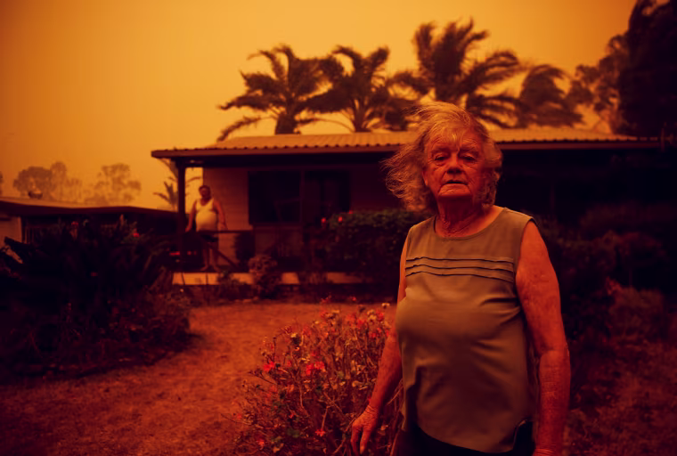 Nancy Allen stands outside a house as high winds push smoke and ash from the Currowan Fire towards Nowra, New South Wales, Australia on Jan. 4, 2020.