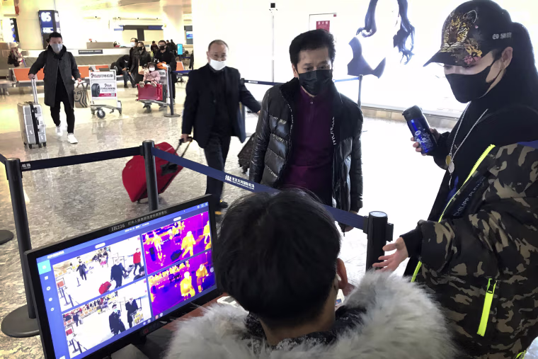 Image: Travelers pass through a health screening checkpoint at Wuhan Tianhe International Airport in Wuhan in southern China's Hubei province