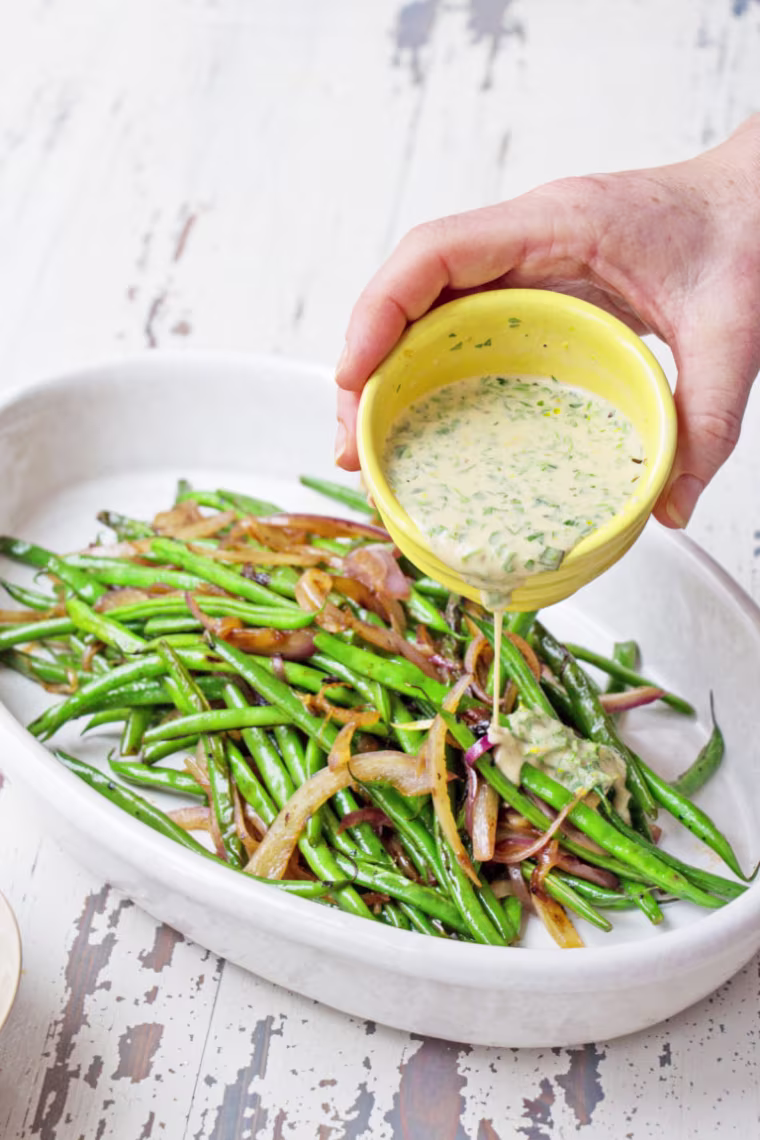 Stir up the dressing and either drizzle if over the whole dish, or pass it at the table for folks to drizzle over their beans as they like.