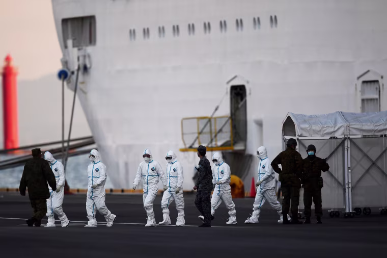 Image: People wearing protective suits walk from the Diamond Princess cruise ship, with around 3,700 people quarantined onboard due to fears of the new coronavirus, at the Daikoku Pier Cruise Terminal in Yokohama