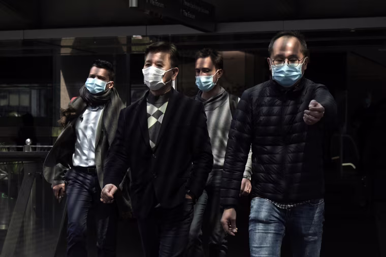Image: People wearing masks walk in Central, a business district in Hong Kong