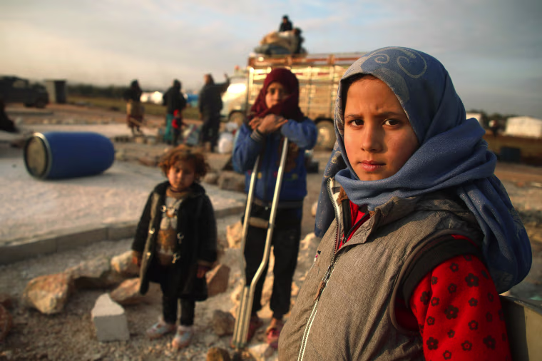 Image: Syrian children pose for a picture as their families prepare to flee a camp for the displaced, east of Sarmada in the north of the northwestern Idlib province