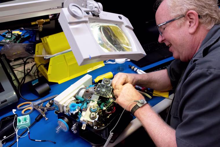 Image: A Ventec Life Systems worker operates on a VOCSN machine, which combines the work of five respiratory medical devices into one.