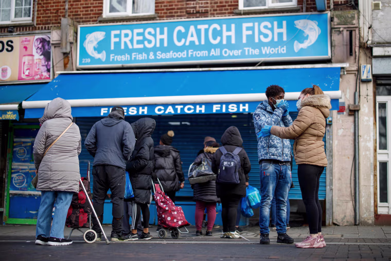 Image: People line up outside a local fishmongers before opening in Walthamstow, east London