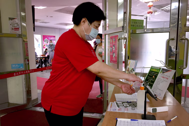 Image: A woman sanitizes her hands before going into a sports center in Taipei. Hand sanitizers are made available in many buildings and businesses in Taiwan.