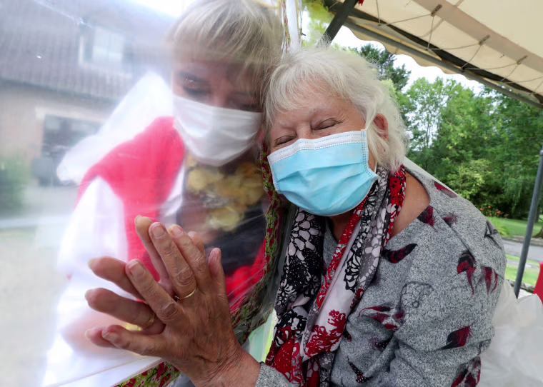 Image: Residents at Belgian nursing home \"Le Jardin de Picardie\" enjoy hugs and cuddle through a wall made with plastic sheets to protect against potential COVID-19 infection in Peruwelz