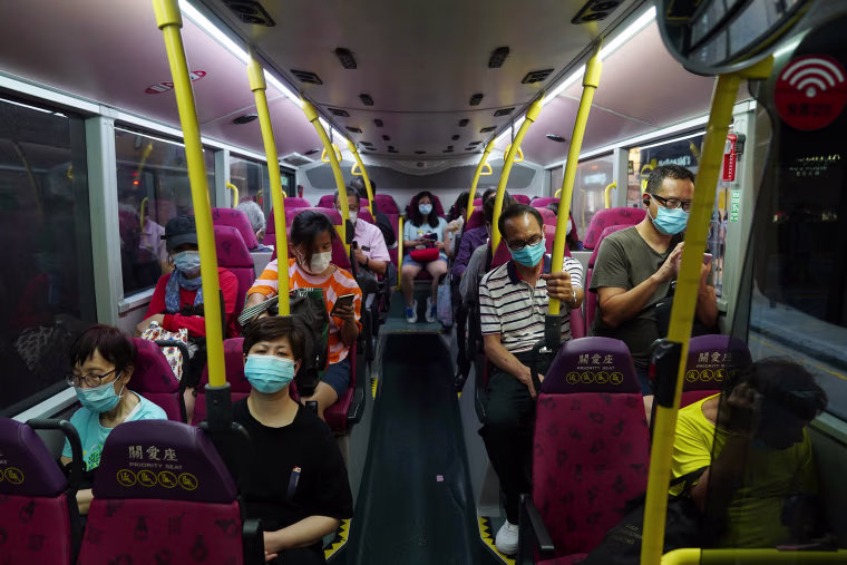 Image: People wearing face masks sit on a bus in Hong Kong