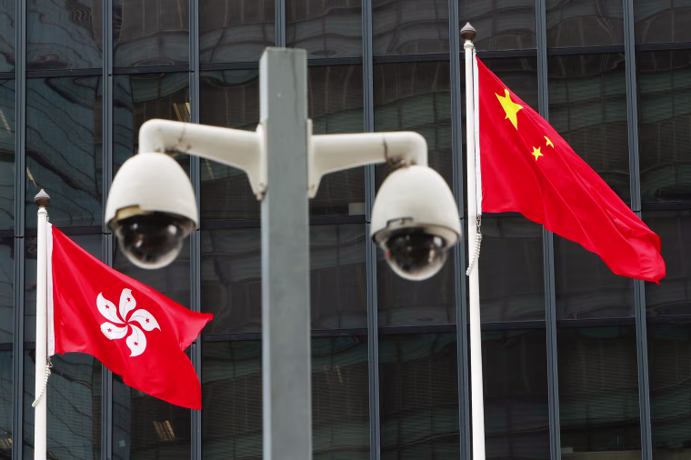 Image: Flags are flown behind a pair of surveillance cameras outside the Central Government Offices in Hong Kong