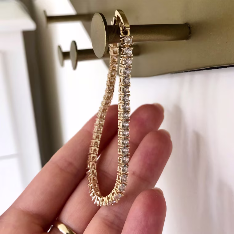 Woman's hand holding Amazon silver and gold tennis bracelet