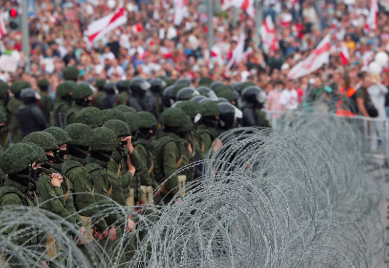 Image: Law enforcement officers stand behind barbed wire during an opposition rally in Minsk on Sunday. 