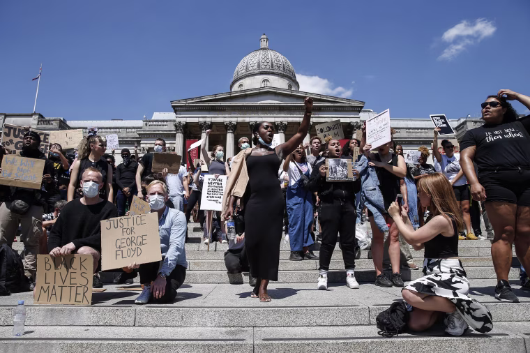 Image: People hold placards as they join a spontaneous Black Lives Matter march at Trafalgar Square