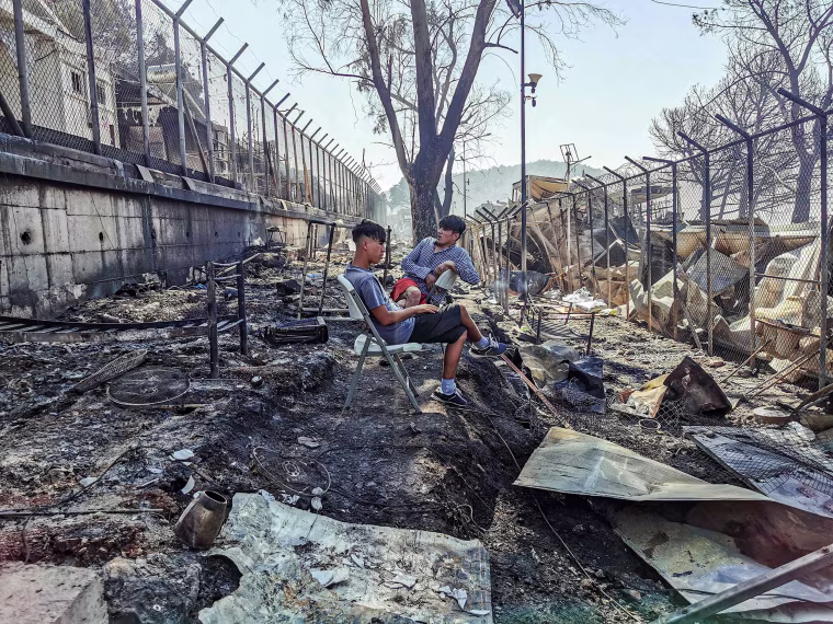 Image: Migrants sit inside the burnt Moria Camp on the Greek island of Lesbos on Sept. 9, 2020, after a major fire.