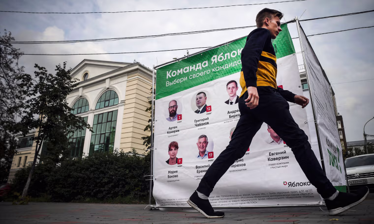 Image: A man walks past an election banner for the Yabloko liberal party in the Siberian city of Tomsk, Russia