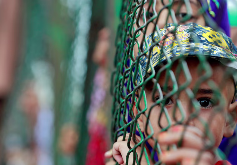Image: Kashmiri child looks from behind a fence at a protest site after Friday prayers during restrictions after the Indian government scrapped the special constitutional status for Kashmir, in Srinagar