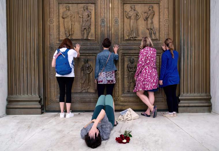 Image: Conservative women who support Judge Amy Coney Barrett's nomination to the Supreme Court, pray while touching the doors of the Supreme Court in Washington as Jacquelyn Booth lays on the ground mourning the death of Justice Ruth Bader Ginsburg on Sa
