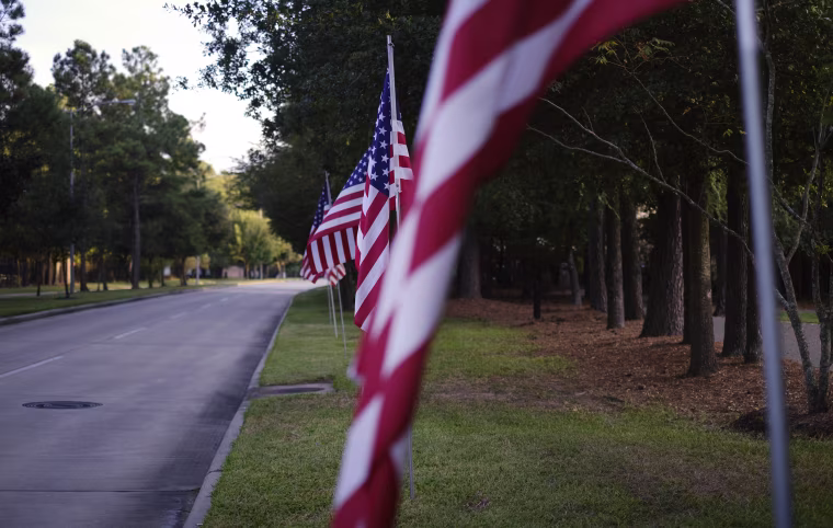 Image: Flags decorate Cutten Road, near a Fallen Warriors Memorial, in Prestonwood Forest.