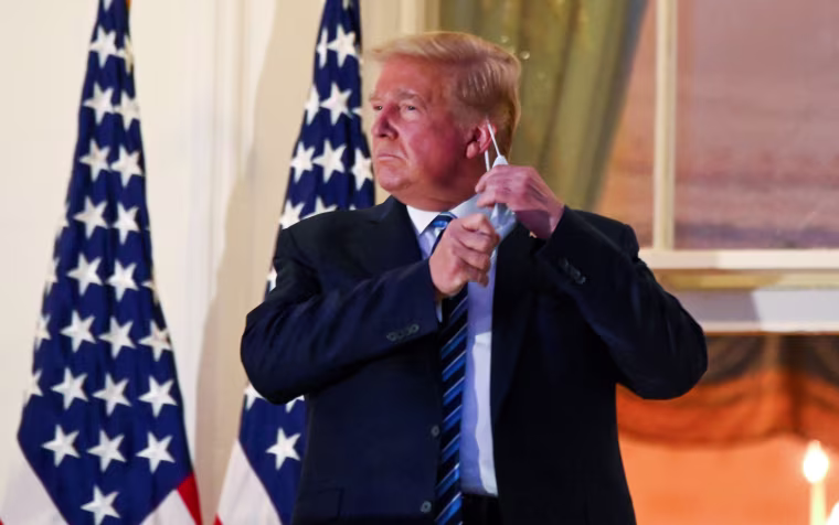 Image: U.S. President Donald Trump pulls off his face mask as he returns to the White House after being hospitalized at Walter Reed Medical Center for coronavirus disease (COVID-19), in Washington