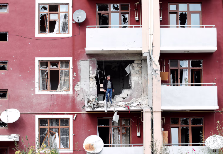 Image: A man looks out from his damaged home after a ceasefire begins during the fighting over the breakaway region of Nagorno-Karabakh in the city of Terter