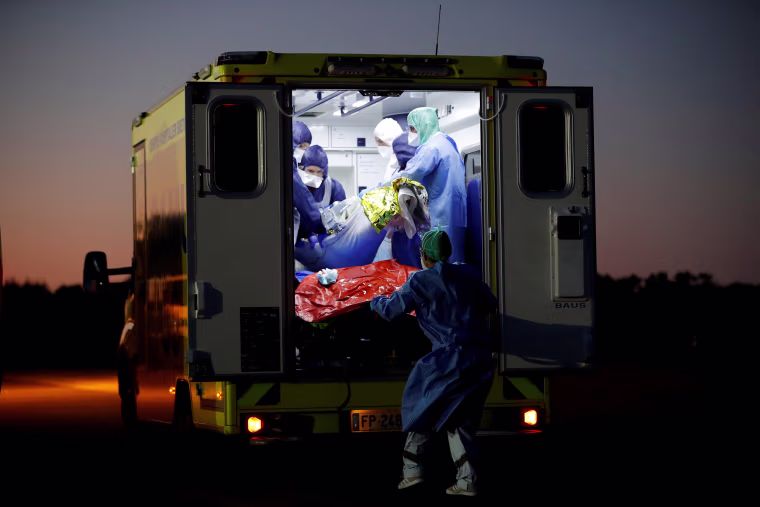 Image: Medical staff members load a patient on an ambulance in France's Vannes Airport.