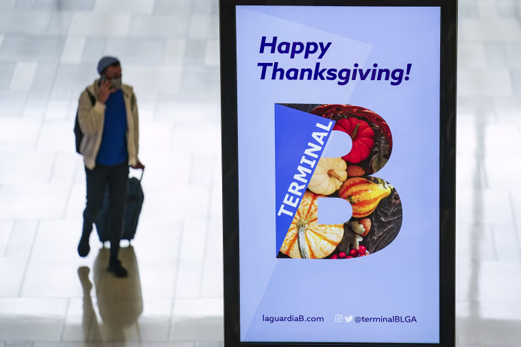 Image: Travelers wearing protective masks to prevent the spread of COVID-19 arrive at LaGuardia Airport