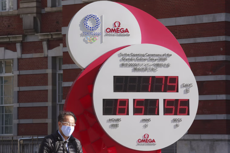 Image: A man walks past a Tokyo Olympic and Paralympic Games countdown clock at the Tokyo train station in Tokyo