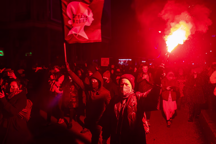 Image: A demonstrator holds a flare as she take part in a pro-choice protest in the center of Warsaw