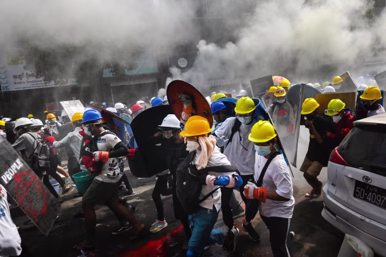 Image: Protesters holding homemade shields as they run during a demonstration against the military coup in Yangon, Myanmar