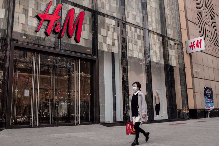 Image: A woman walks past a store of Swedish clothing giant H&amp;M in Beijing