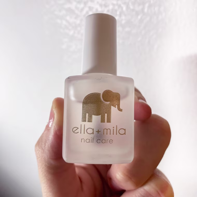 Emma Stessman holding up a bottle of the ella+mila Nail Care