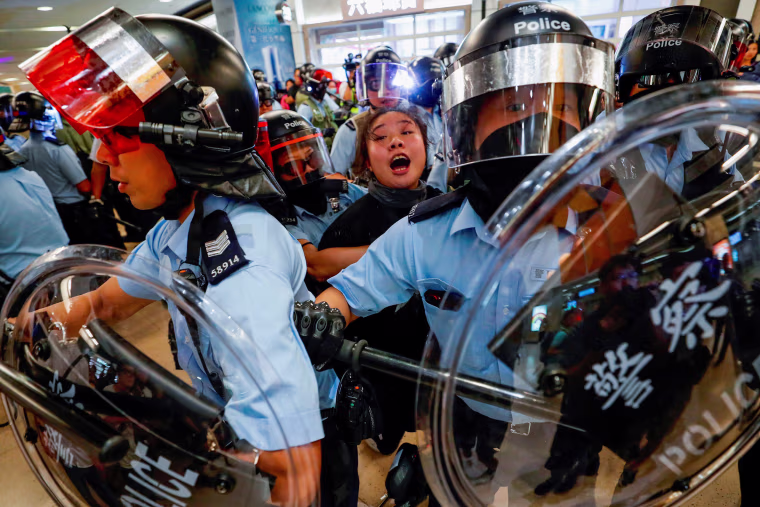 Image: Riot police detain a woman as anti-government protesters gather at Sha Tin Mass Transit Railway station in Hong Kong,