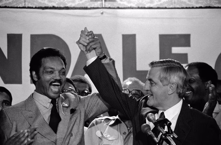 Image: The Rev. Jesse Jackson, left, and Democratic presidential nominee Walter Mondale lift their arms in St. Paul, Minnesota on Aug. 29, 1984, after Mondale met with Black leaders.