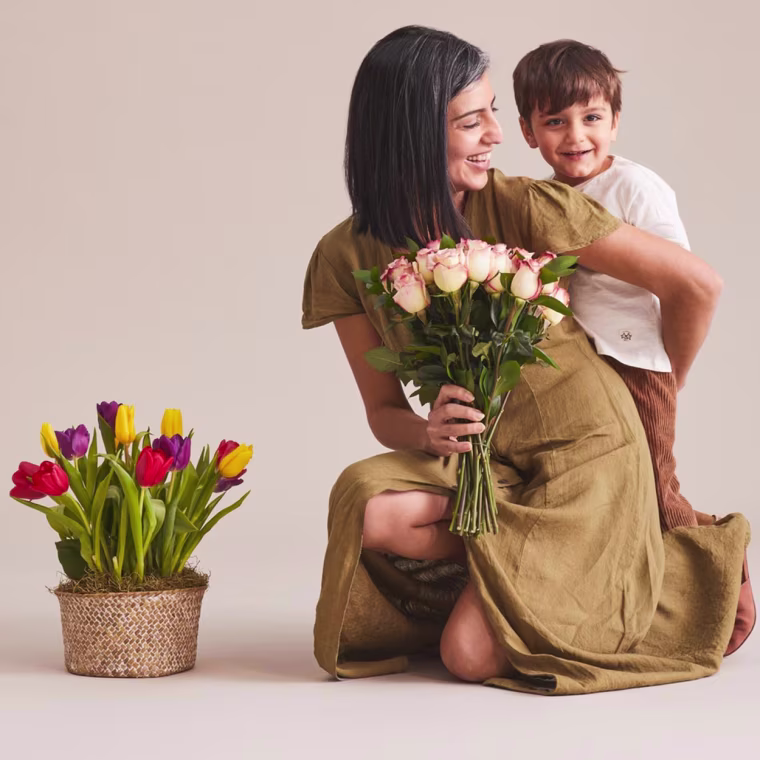 Mom hugging her son while holding flowers