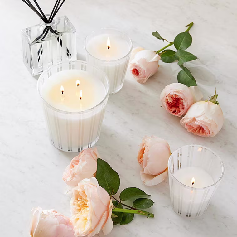 Image of white candles from Nest surrounded by roses
