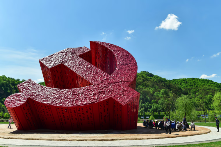 Image: Tourists watch a sculpture featuring the emblem of Communist Party of China at a square of Nanniwan Town on May 17, 2021 in Yan'an, Shaanxi Province of China.