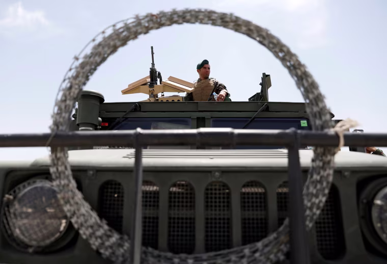 Image: An Afghan security forces member keeps watch as he sits in an army vehicle at Bagram Airfield after American troops vacated it.