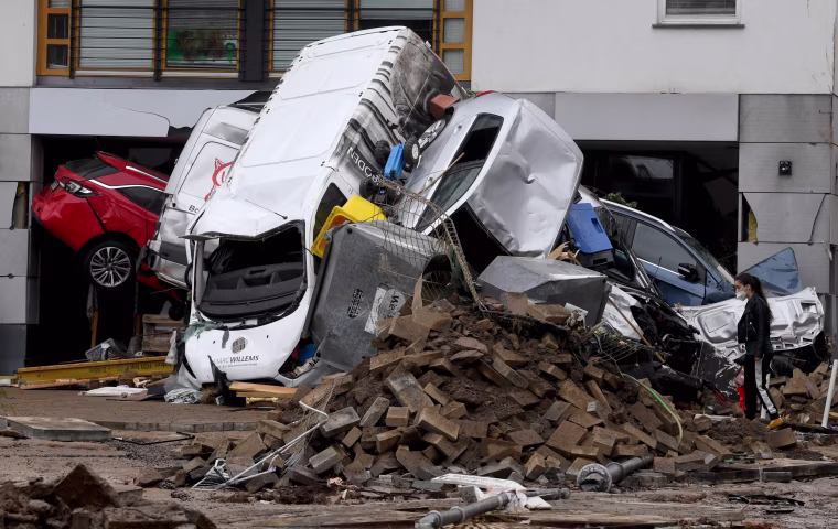 A woman looks at cars and rubble piled up in a street in Bad Neuenahr-Ahrweiler, western Germany, on July 16, 2021.