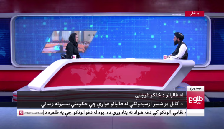 Image: A female news anchor talks to a member of the Taliban on Afghan news channel Tolo News.
