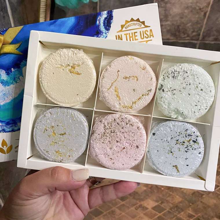 Image of Writer Terri Peters holding a set of 6 tablets, from an aromatherapy shower steamer set