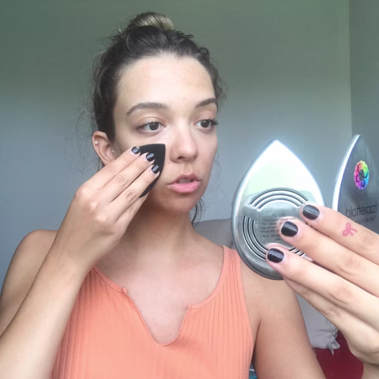 Writer Cailey Rizzo blotting her face with an oil blotter
