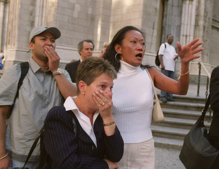People in front of New York's St. Patrick's Cathedral react with horror as they look down Fifth Ave towards the World Trade Center towers after planes crashed into their upper floors.