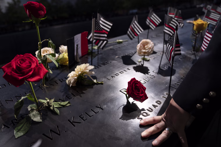 A firefighter places his hand on the name engravings on the south pool during ceremonies in New York.