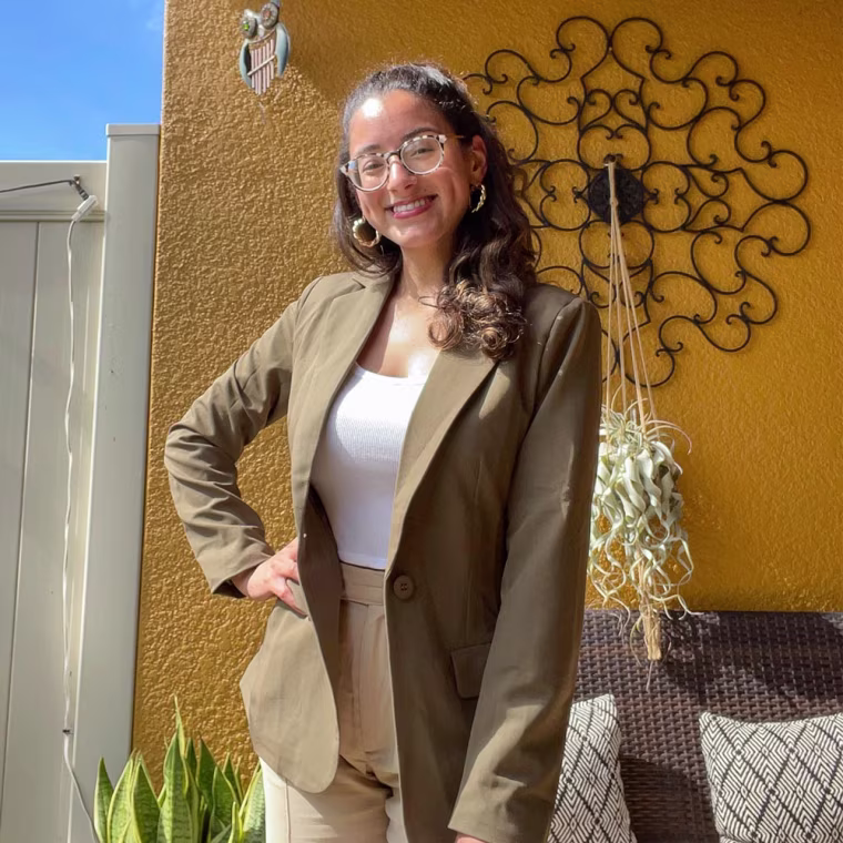 Writer Jillian Ortiz wearing an olive blazer outside
