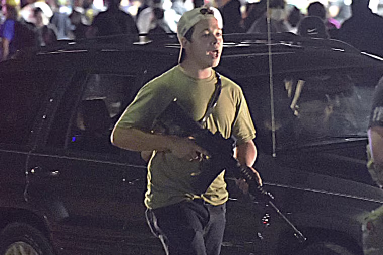 Kyle Rittenhouse carries a weapon as he walks along Sheridan Road in Kenosha, Wis., on Aug. 25, 2020.