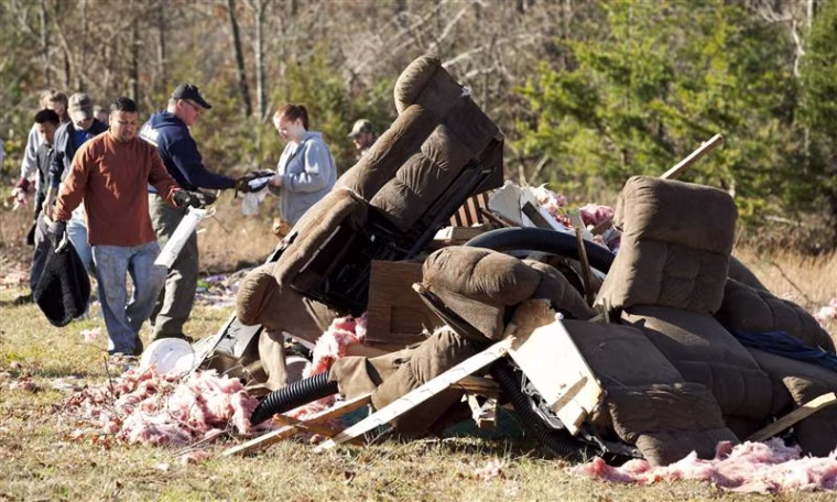 People clean up the home of Byron Cole after it was damaged by a possible tornado on Piney Mountain Road near Ellenboro
