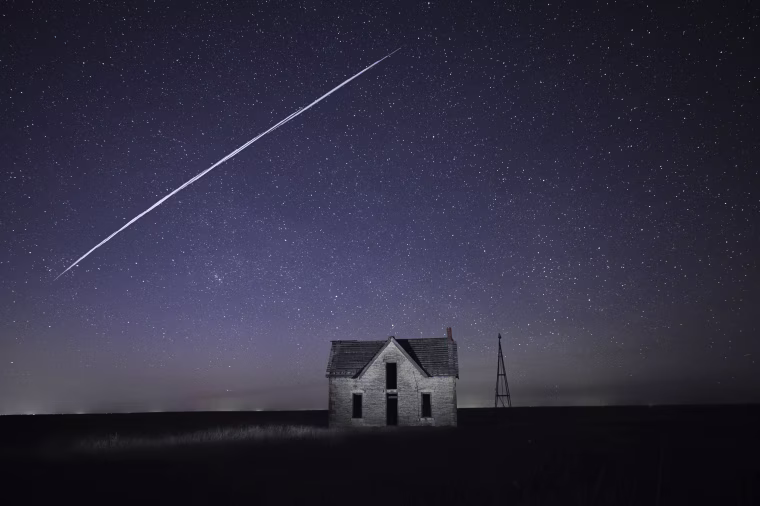 A string of SpaceX StarLink satellites passes over an old stone house near Florence, Kan., on May 6, 2021.