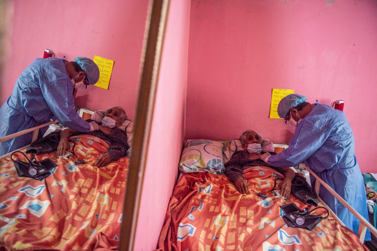 Image: A healthcare worker checks on Maria Tafur before giving her Covid-19 vaccine in Lima, Peru, on April 28, 2021.